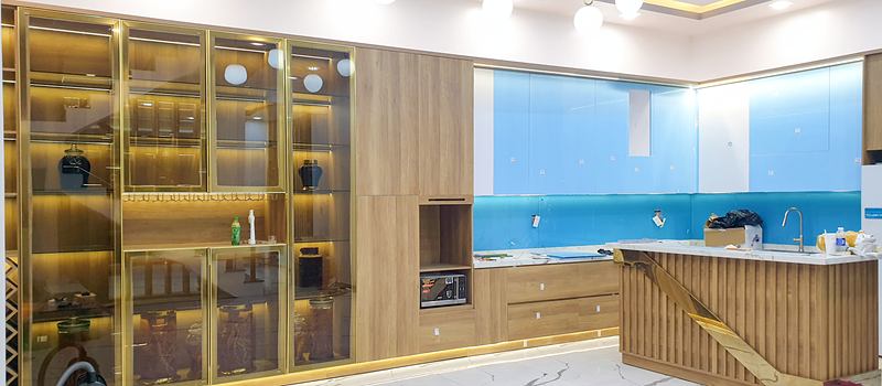 Khu bếp với tủ trưng bày cánh kính, tủ bếp vân gỗ sáng và quầy bar