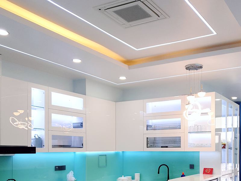 Tủ bếp trên trắng bóng với các khoang cánh kính lắp đèn và kính ốp bếp màu xanh ngọc